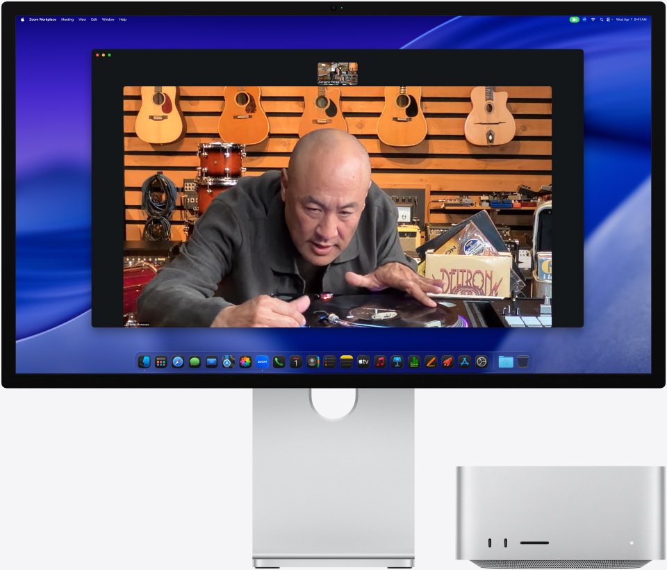 Durante una videollamada en un Studio Display XDR con el Mac Studio debajo, una persona en una tienda de música examina de cerca un tocadiscos