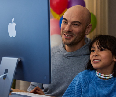 Un adulto y un menor trabajan en una iMac azul