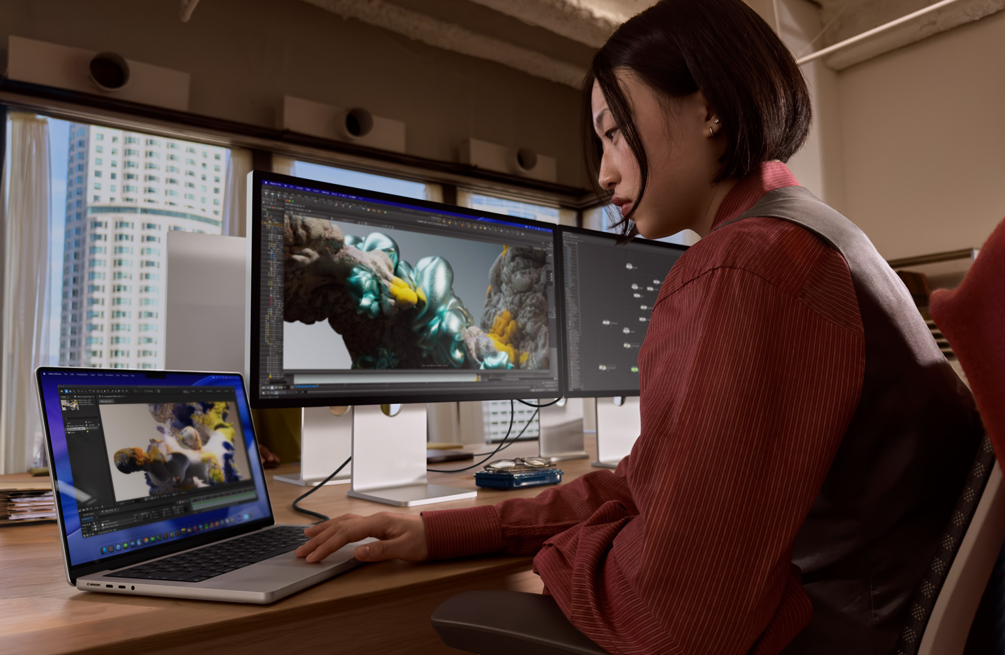 Uma pessoa em um escritório trabalha em um notebook MacBook conectado ao Studio Display XDR por uma porta Thunderbolt 5