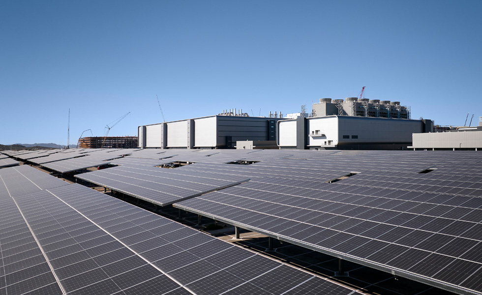 Reihen von Solarpaneelen neben einem Industriegebäude unter klarem blauem Himmel
