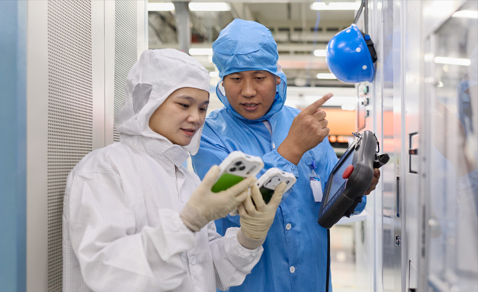 Zwei Personen in vollständiger Schutzkleidung arbeiten gemeinsam an zwei iPhone Geräten